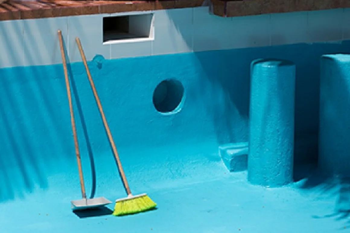 Leerer, frisch gestrichener Pool mit Besen